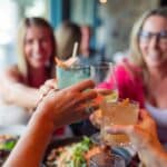 Happy hours : un levier subtil mais puissant pour faire grimper le chiffre d’affaires A group of people sitting at a table with drinks